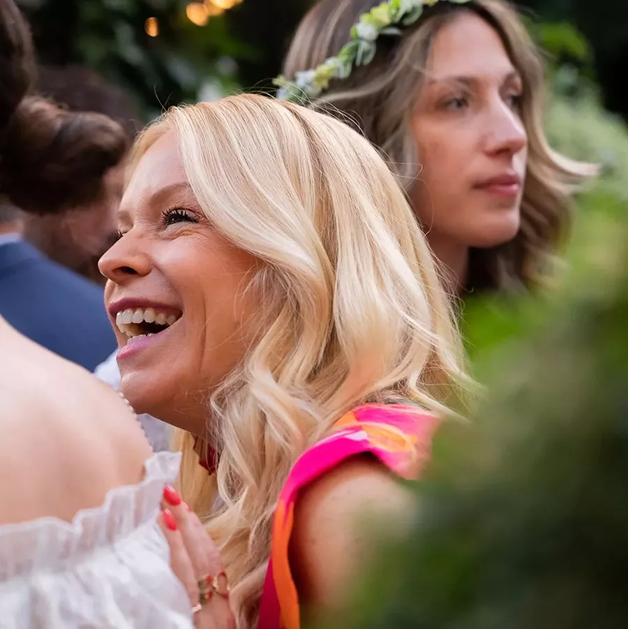 Blond woman laughing and another woman in the background gazing into the distance
