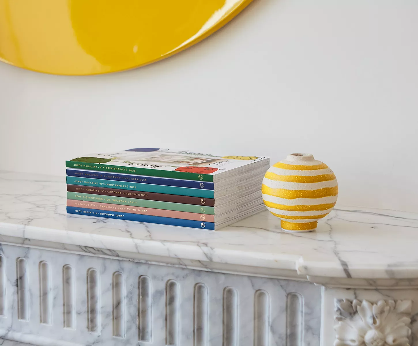Stack of Junot Magazines placed on a white marble mantelpiece