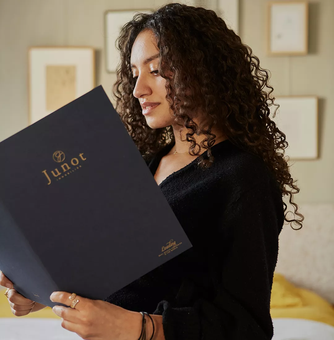 Un locatrice Junot lit la brochure Junot pour la location d'un bien de luxe avec Junot location & gestion