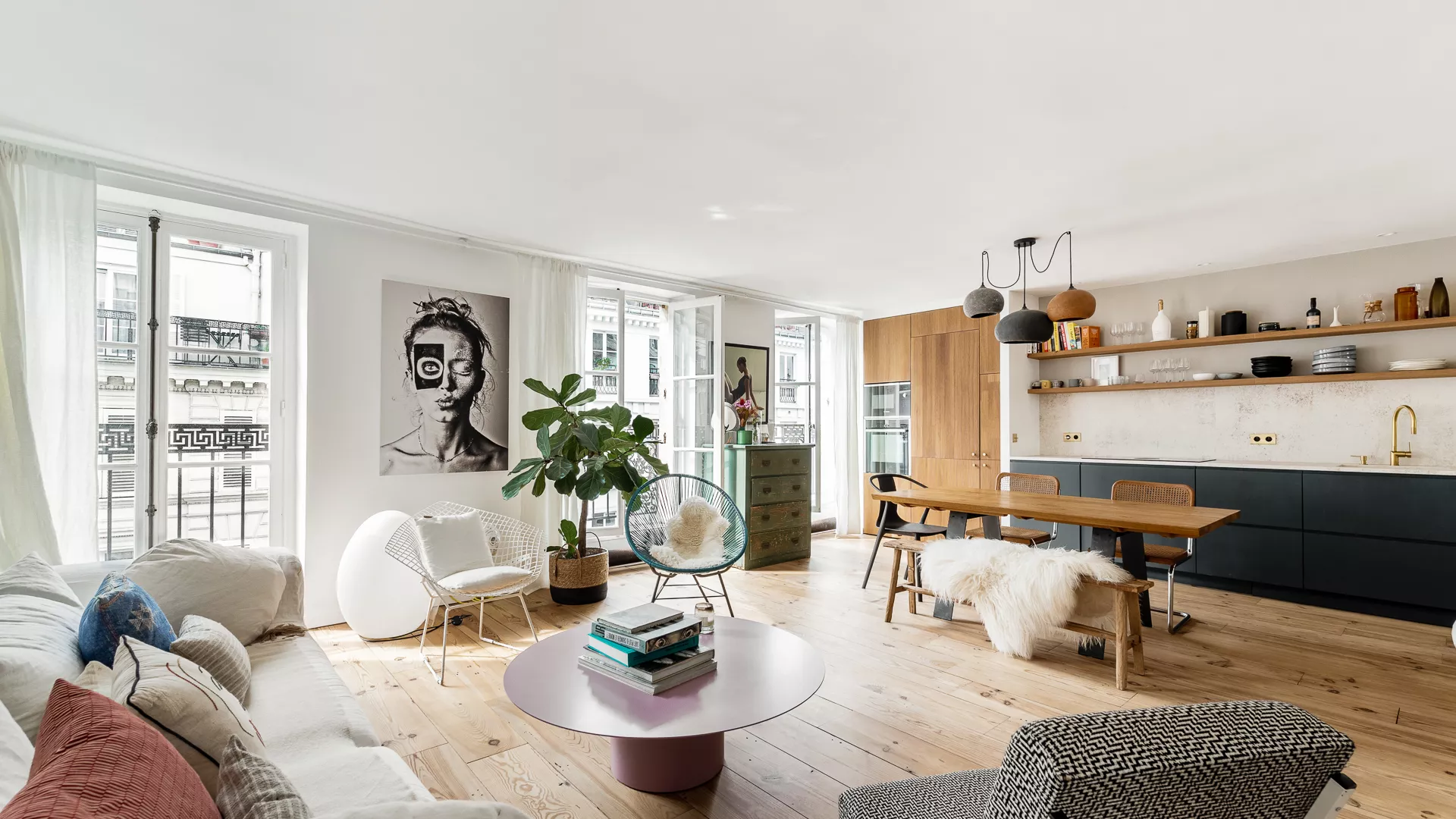 Salon lumineux avec cuisine ouverte d’un appartement dans le 9ᵉ arrondissement de Paris, ouvert sur un balcon.