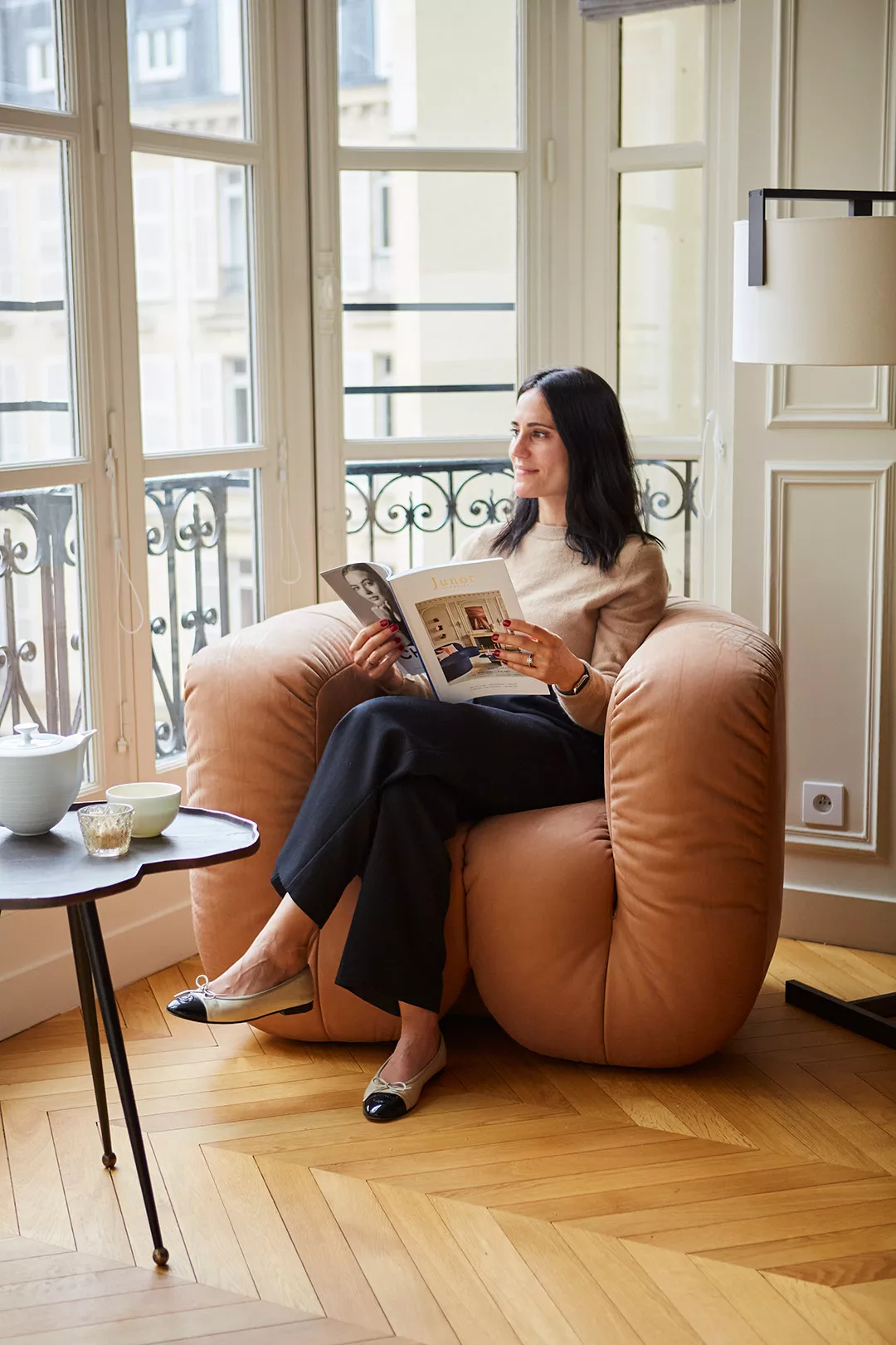Cliente Junot en train de lire assisse dans un fauteuil de designer d'un appartement vendu à Paris par Junot