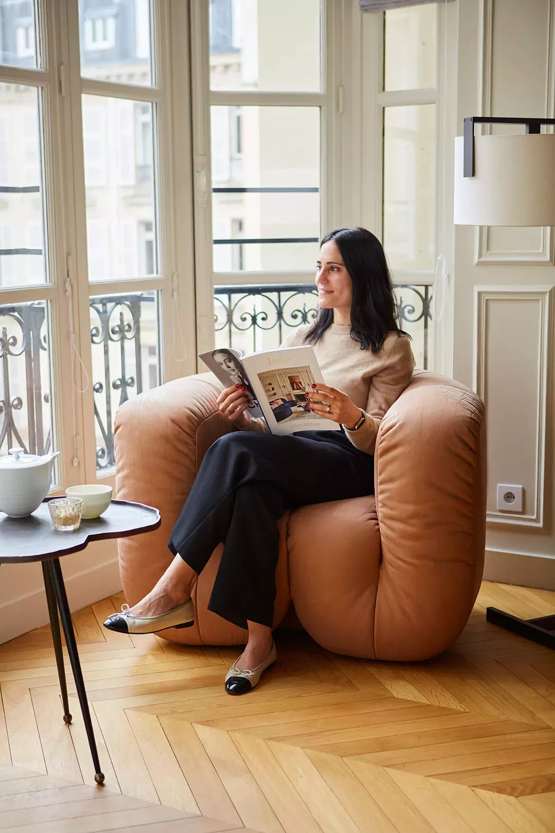 Woman reading Junot Magazine Sitting on a brown armchair
